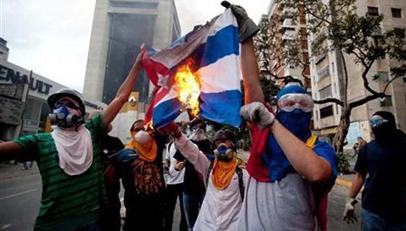 Miembros de la oposición venezolana queman una bandera cubana.